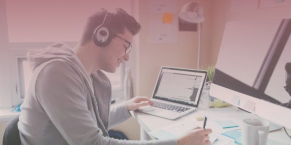 Man wearing headphones listening to remote work playlist while writing