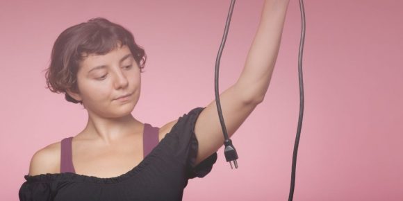 Woman holding an unplugged extension cord to show the meaning of detaching from work