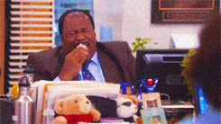 Man hysterically laughing while waving hand and wiping eyes with tissue