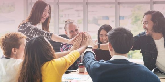 Team of employees working on community building by sharing a high-five