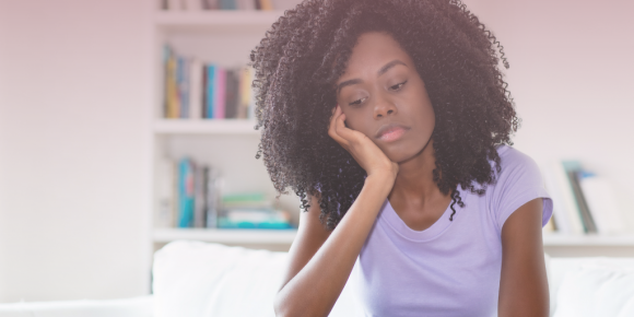 Young woman sitting a desk looking upset due to imposter syndrome