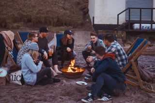 Employees gathered around a fire on the beach for a remote team retreat