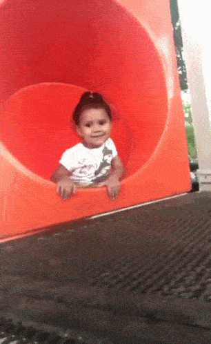 Little girl waving goodbye while sliding down a slide