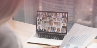 Woman looks over meeting notes while on a video call with multiple team members